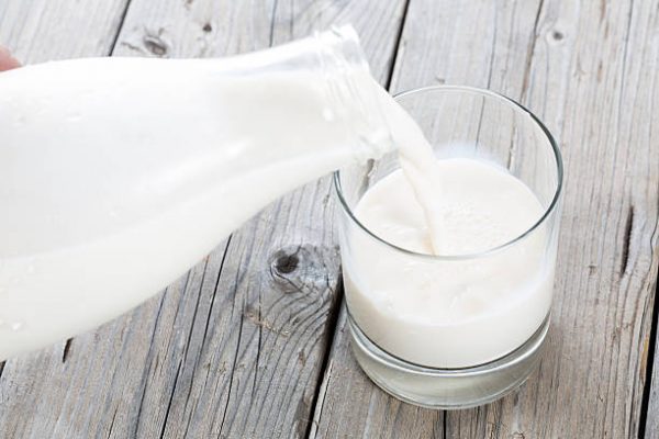 Serving fresh milk in a glass vase on a wooden table